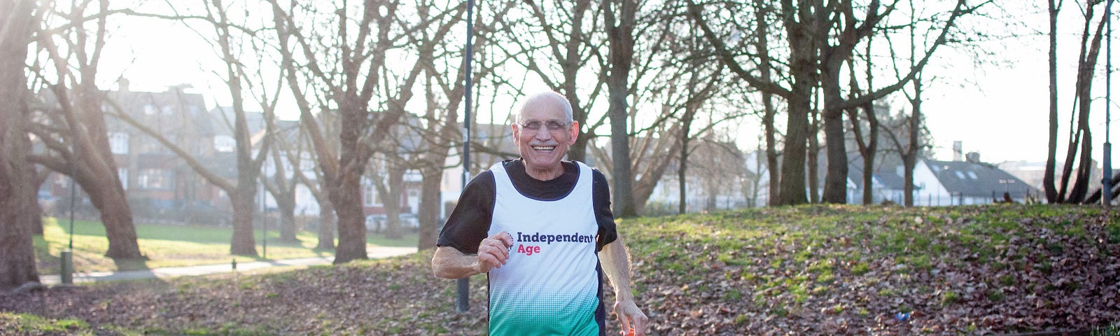 Older man running in park wearing training vest with Independent Age logo