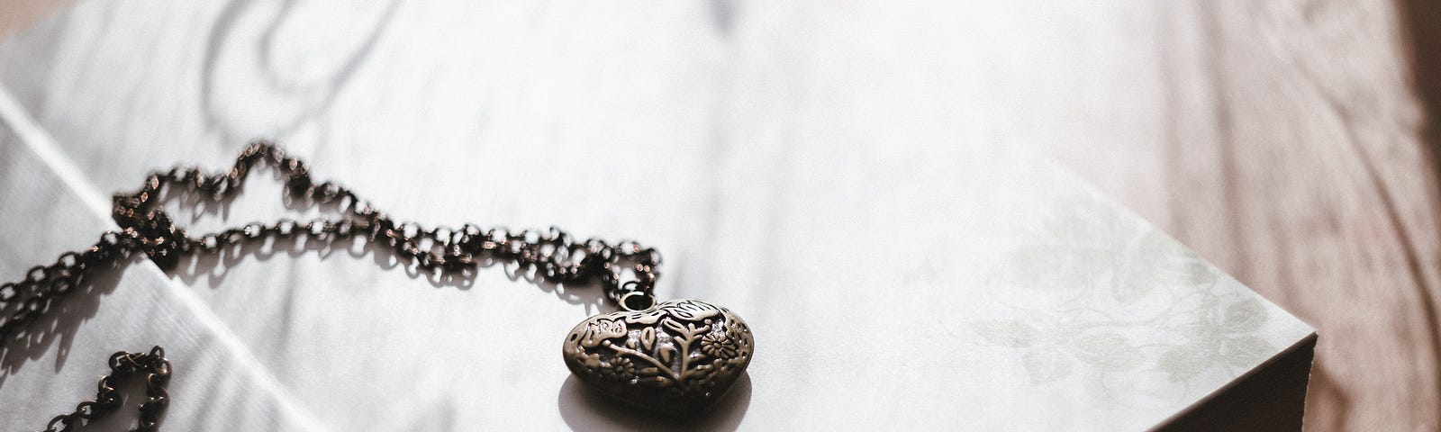 An antique heart locket necklace lying on top of a table.