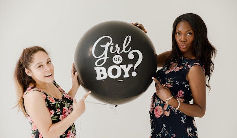 Pregnant women holding girl or boy balloon