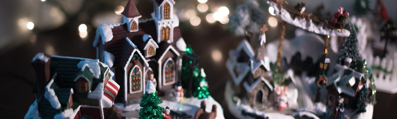 Two miniature scenes of gingerbread houses and Christmas trees in the snow.