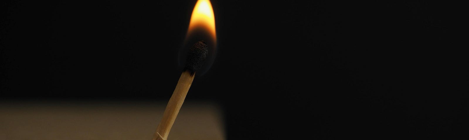 Lighted Matchstick on Brown Wooden Surface