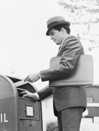 1950’s man in a suit posting a letter in an American letter box
