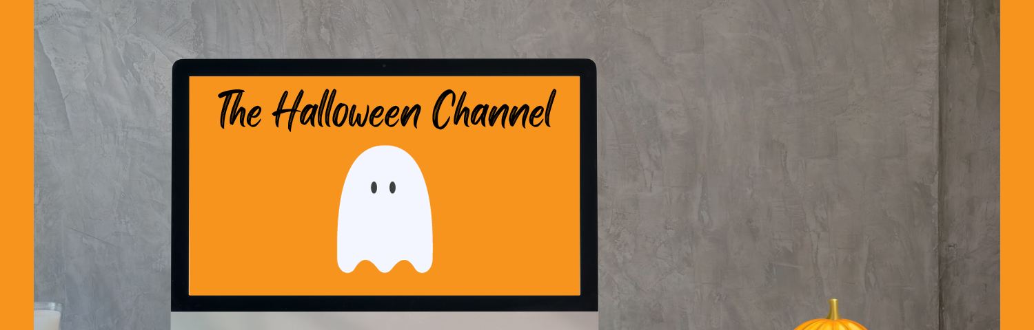 White desk in front of gray background. Computer monitor on desk shows The Halloween Channel title and logo ghost on orange background. Jack ‘O Lantern sits on desk.