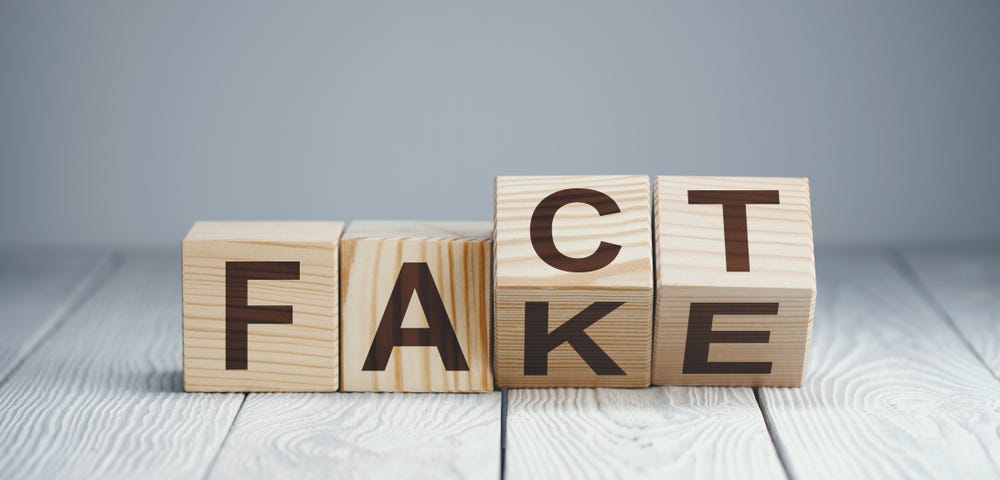 Four blocks with two tilted, so that both the word fact and fake can be read