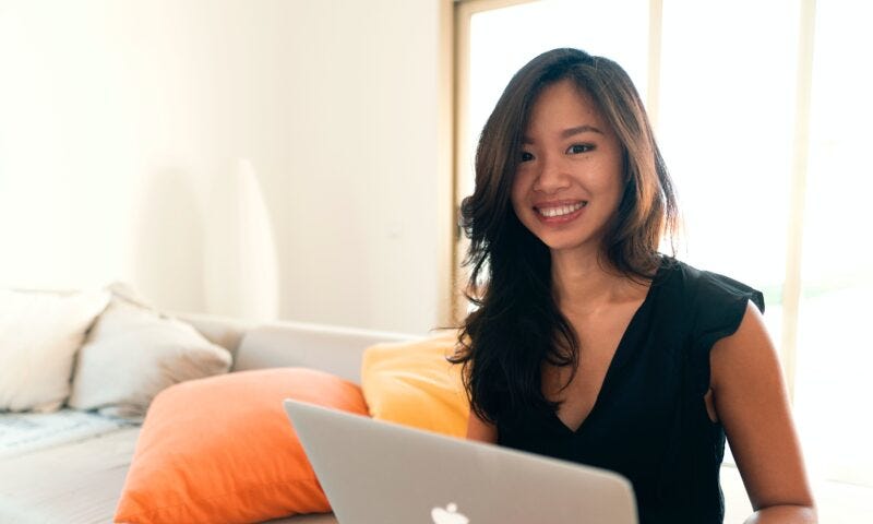 a smiling woman sits with her laptop creating a safe digital container for her clients