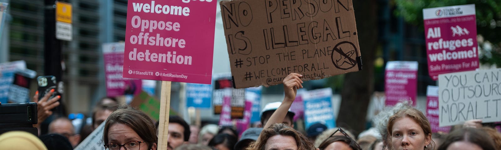 A crowd of protesters hold signs welcoming refugees and opposing offshore immigration detention.