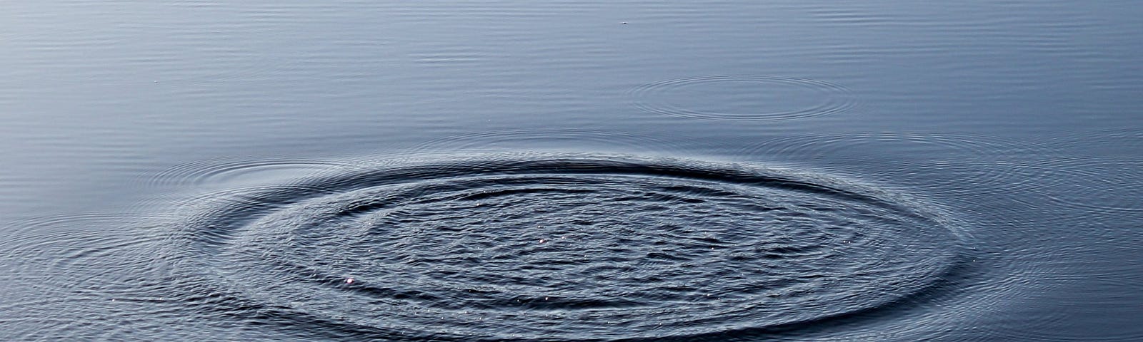 Photo of Watery ripples on an otherwise tranquil glassy blue lake