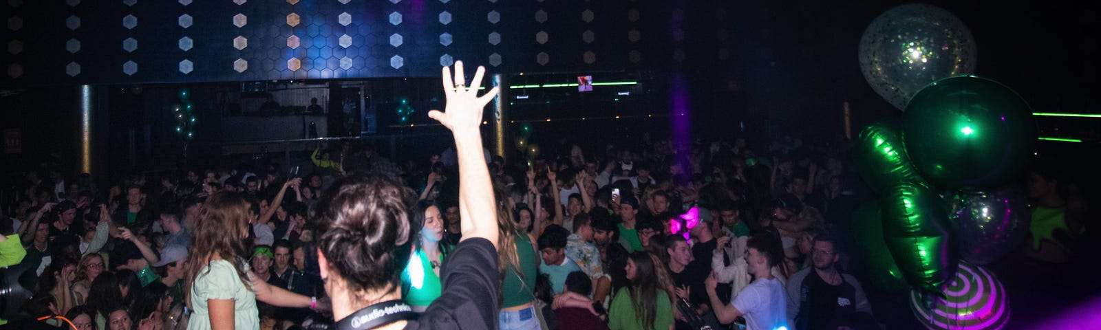 DJ raises his hand facing a crowd of party goers at Enso nightclub.