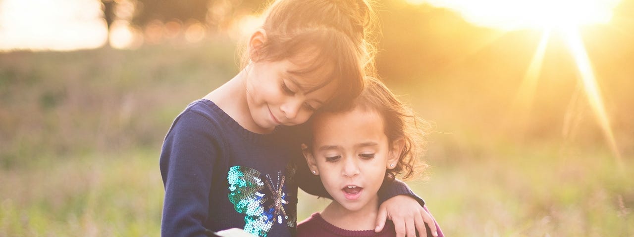 A young girl helping her little sister read the Bible