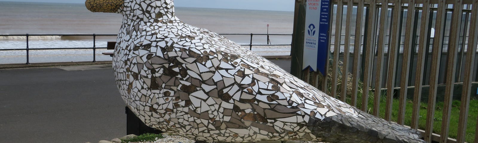 A large white and grey herring gull statue made from mosaic pieces.