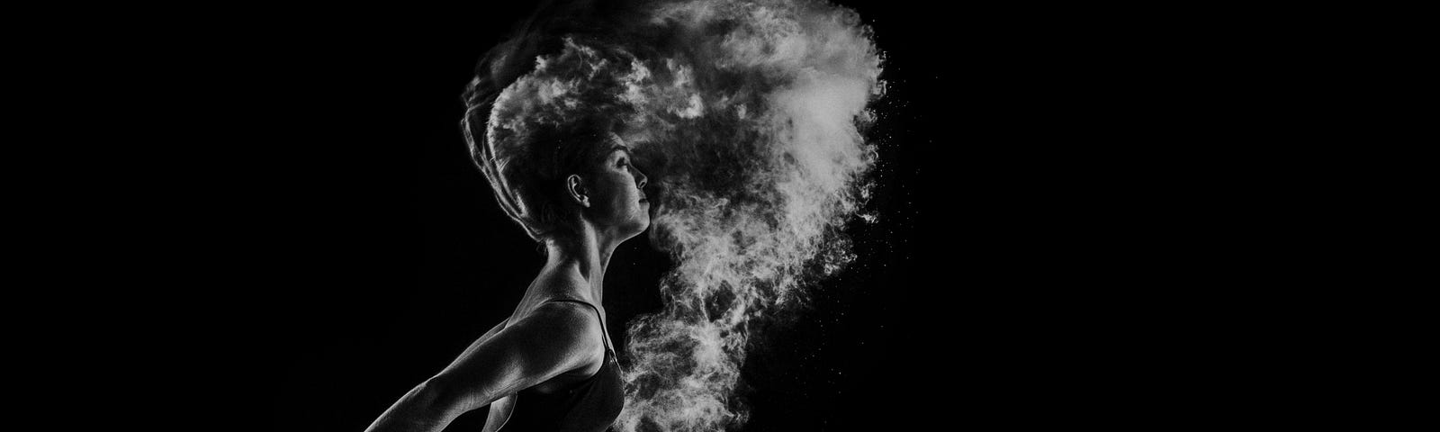 A woman underwater with her hair flowing and water exploding around her
