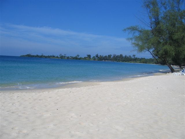 White sand, trees around a bay and deep blue ocean. Sihanoukville, Cambodia.