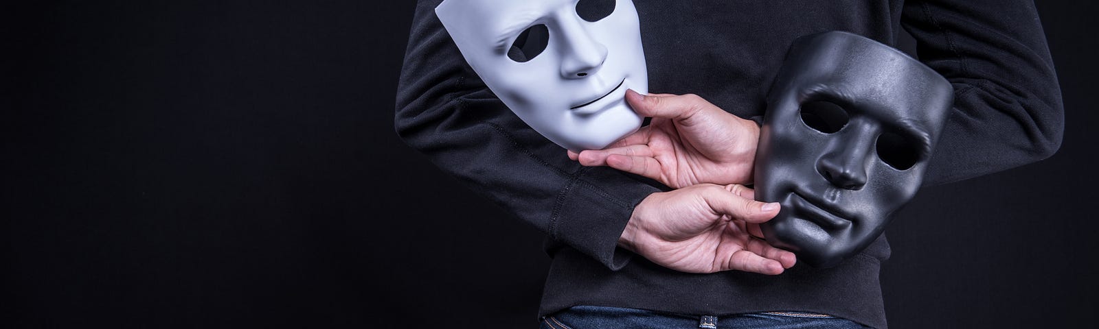 a man holding one black and one white mask behind his back