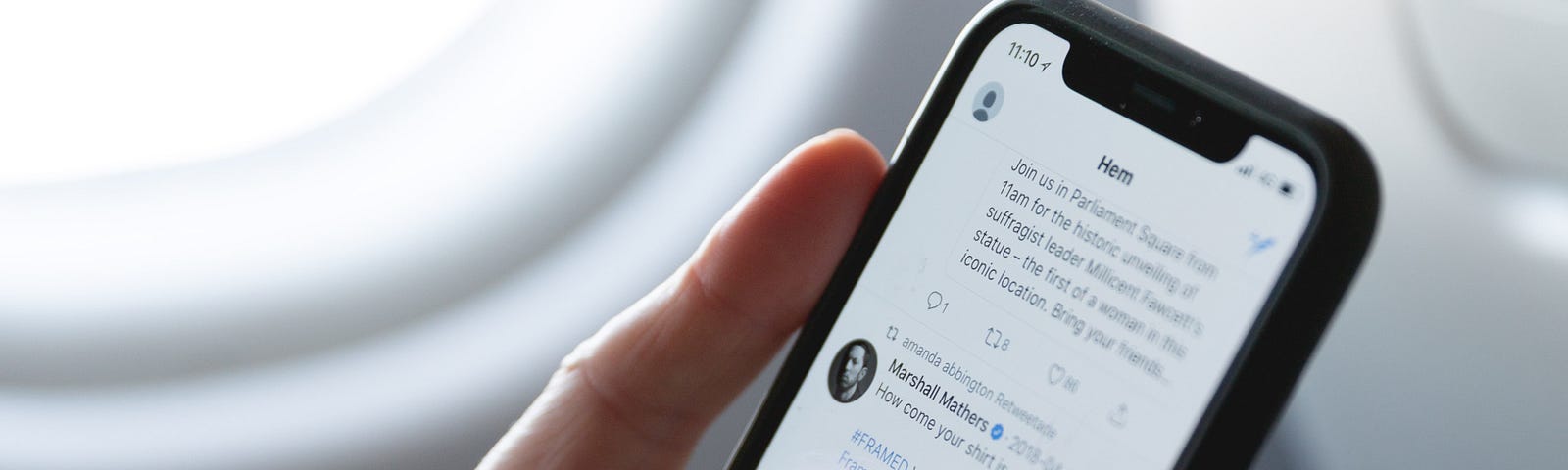 A person browses their twitter feed while sitting on an airplane.