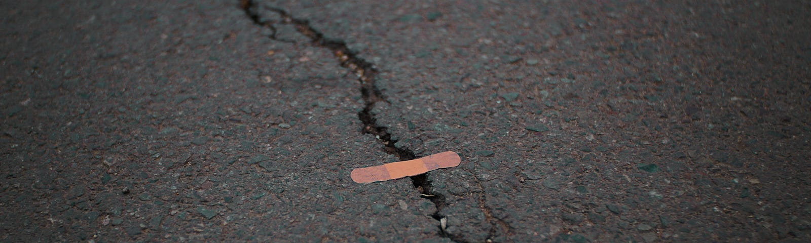 A crack in the road patched with a band-aid.