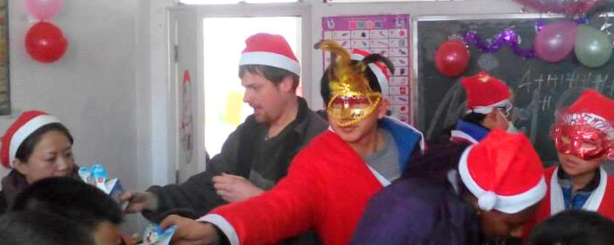 Evan wearing a Santa hat and passing out presents to students.