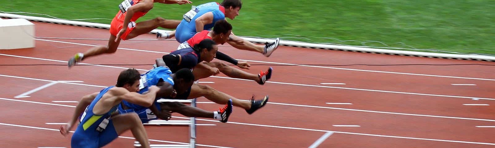 Athletes jumping over a hurdle in a race