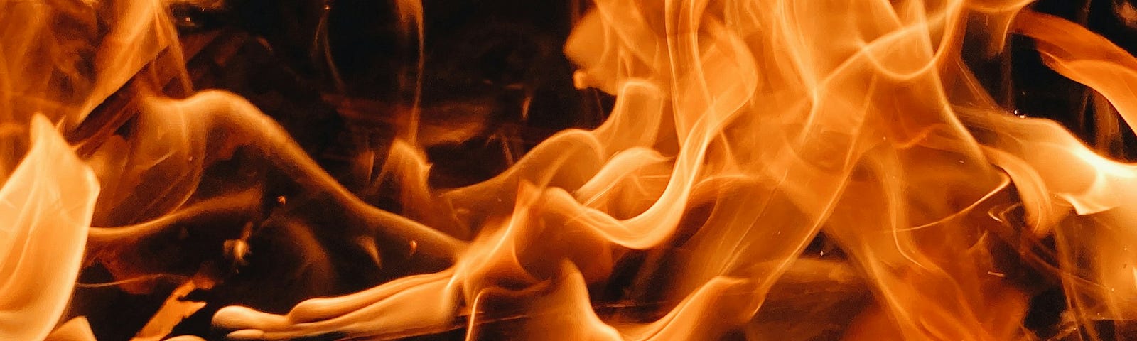 Close shot of intense orange flames contrasted by black embers