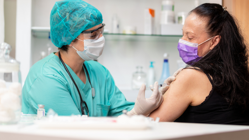 Medical professional provides a vaccination to an older woman.