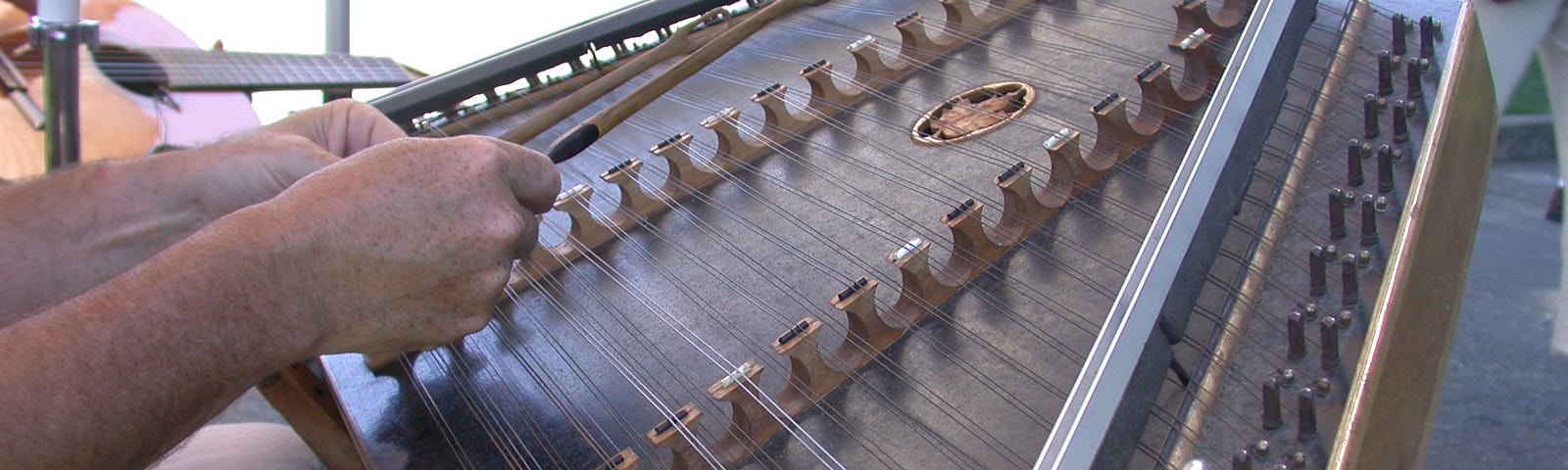 A musician playing a Hammered Dulcimer, a stringed-percussion instrument, in public.