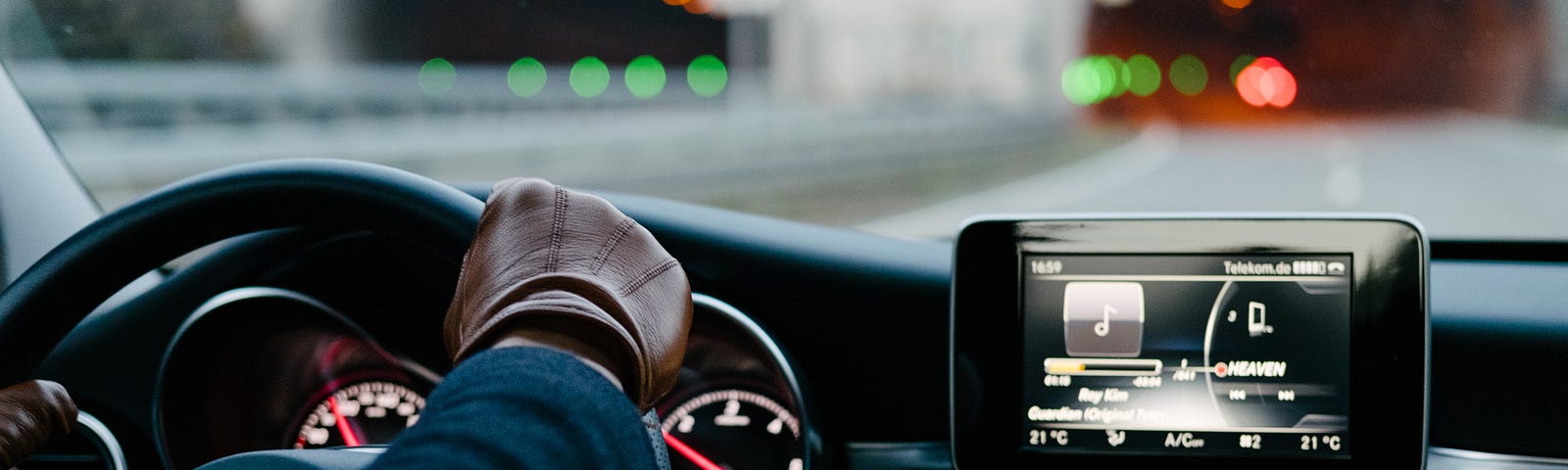 A person wearing brown leather gloves drives a car into a tunnel.