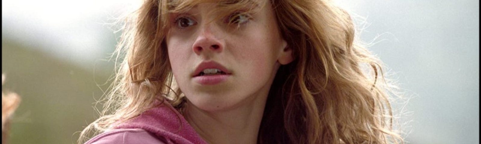 Closeup of a teenage Emma Watson as Harry Potter series Hermione Granger wearing a pink hoodie.
