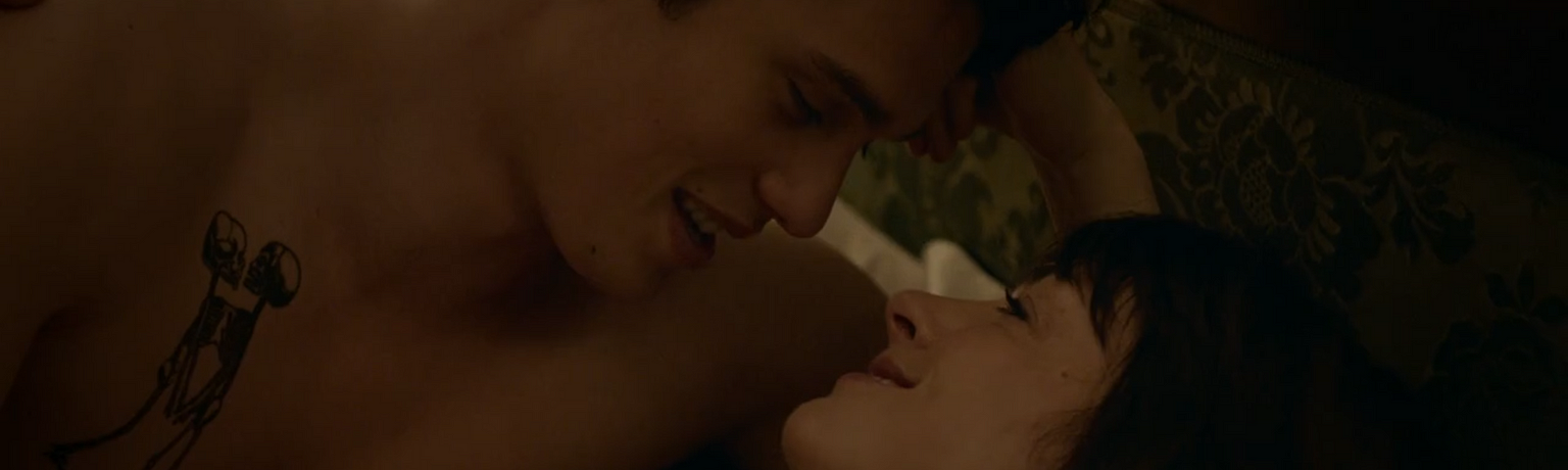 Anne Hathaway and Nicholas Galitzine in ‘The Idea of You’, smiling at each other in bed.