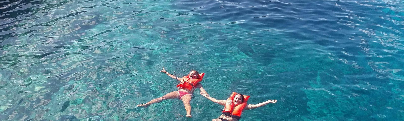 Two women in life vests floating in ocean