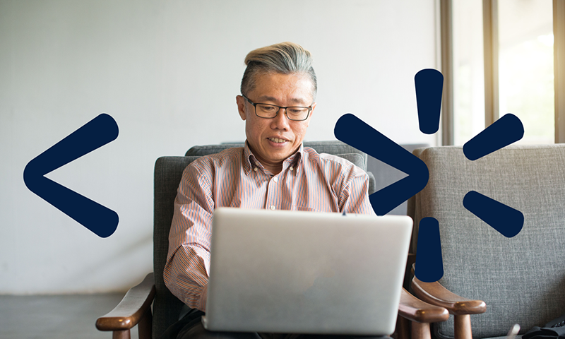 A man wearing glasses working on a laptop.