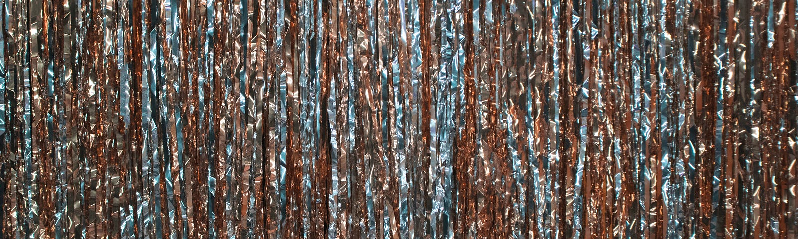 Photo by DESIGNECOLOGIST on Unsplash — wall of red and blue shiny tinsel hanging down.