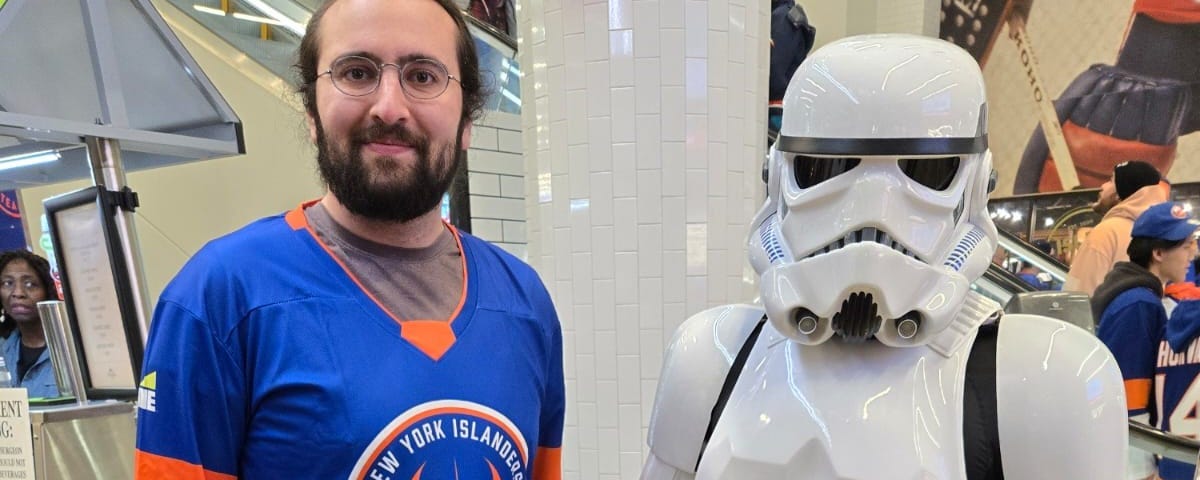 I stand next to a stormtooper. I have on a blue and orange Jedi themed hockey jersey.