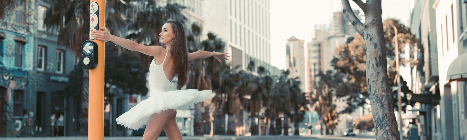Ballerina posing in the street by a traffic light