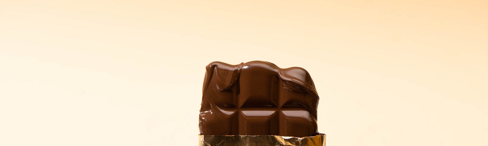 Cropped View of Woman Holding Delicious Milk Chocolate Bar in Golden Foil Isolated on Beige