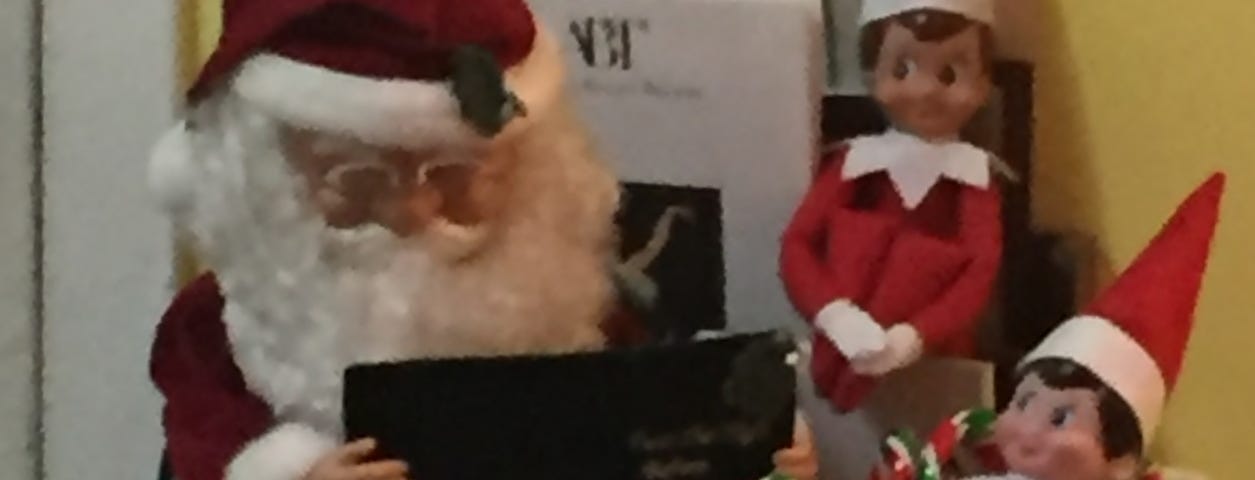 Figures of Santa Claus and two elves on the shelf