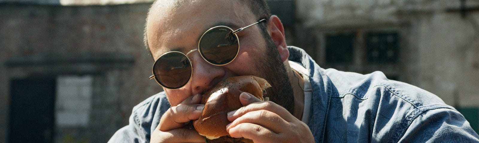 Large man eating a large hamburger.