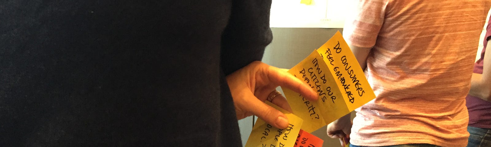 A person from behind holding several Post-it notes between his fingers while attending the NCredible Framework Workshop.