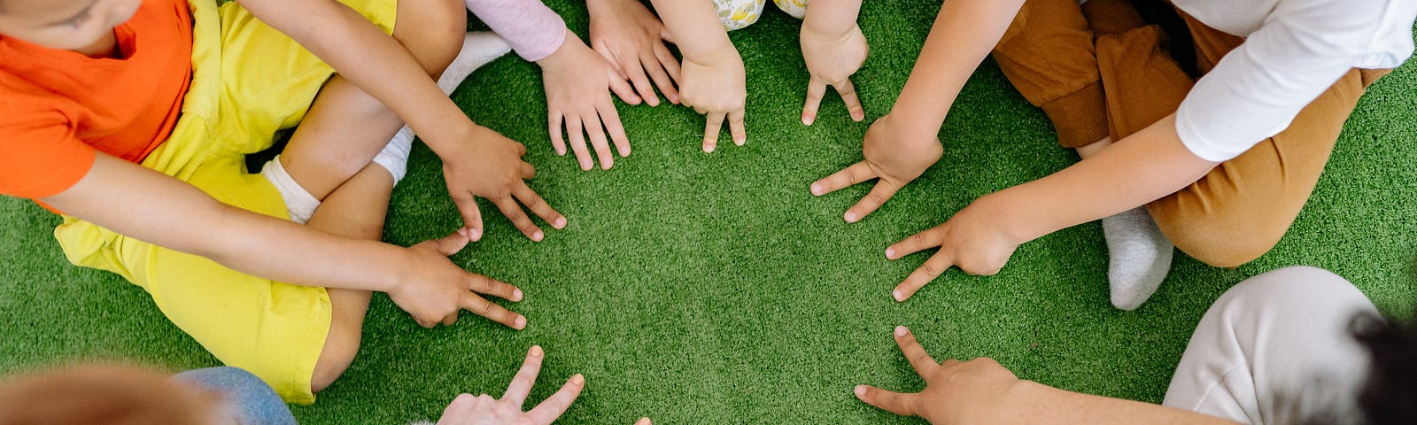 School children sit in a circle, with hands in middle.