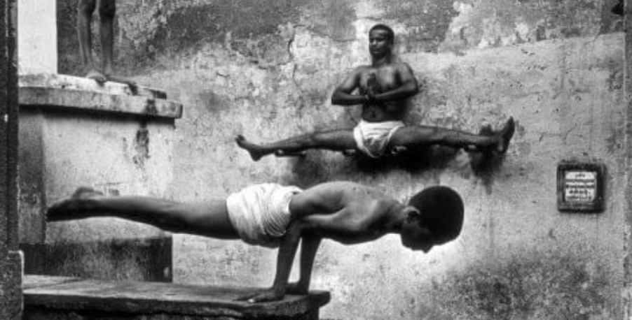 a black and white photo of 2 people doing calisthenics.