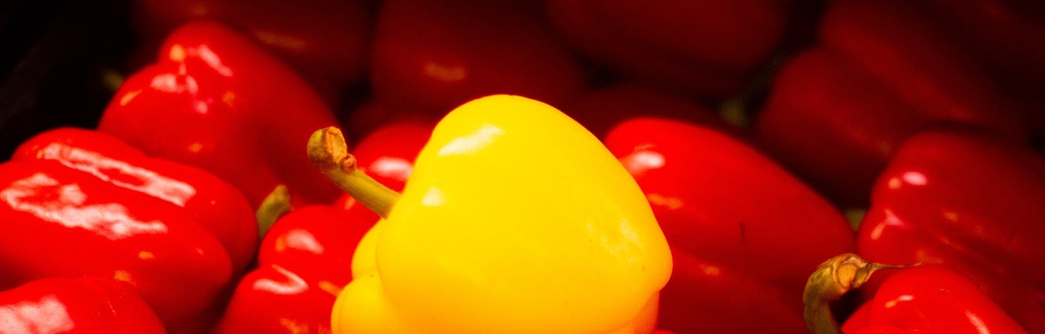 Yellow pepper atop red peppers.