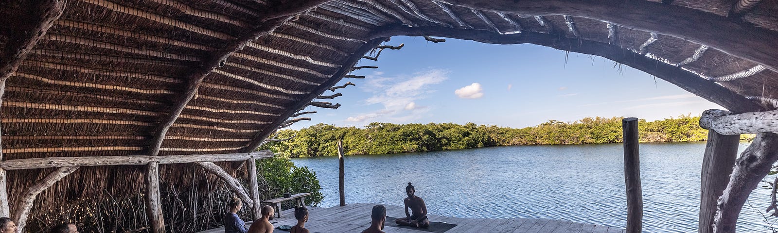 people sitting cross legged in a meditation circle, facing a lake