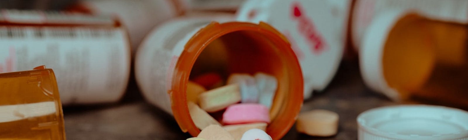 An overturned prescription bottle spills colorful heart-shaped candies writing xoxo on