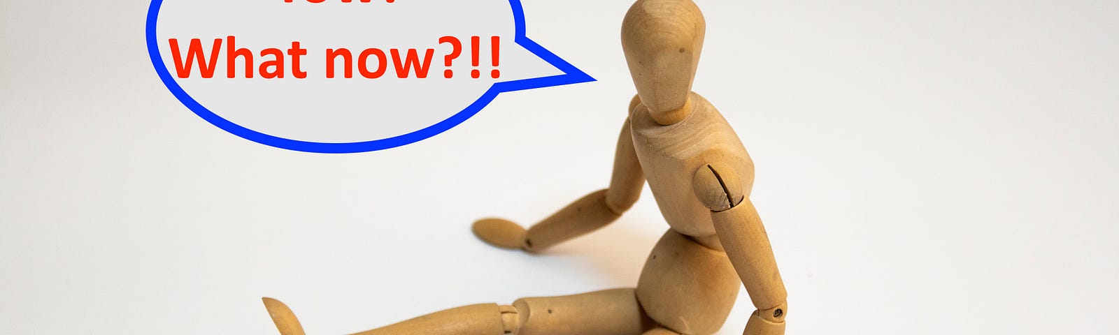 A wooden mannequin sits on the floor, legs outstretched. His speech bubble reads: “Yow! What now?!!”