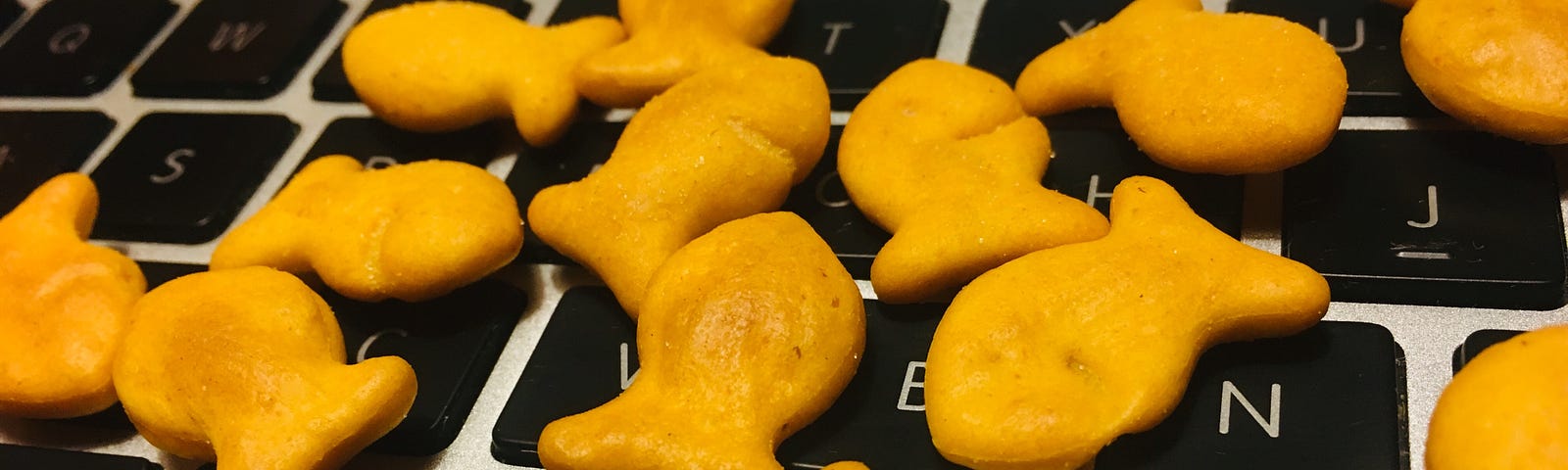 Computer keyboard strewn with goldfish crackers.