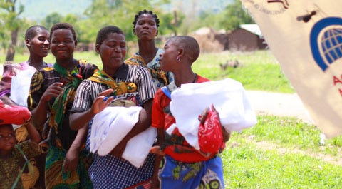 Un groupe de personnes africaines transportant des moustiquaires. Source : Against Malaria Foundation