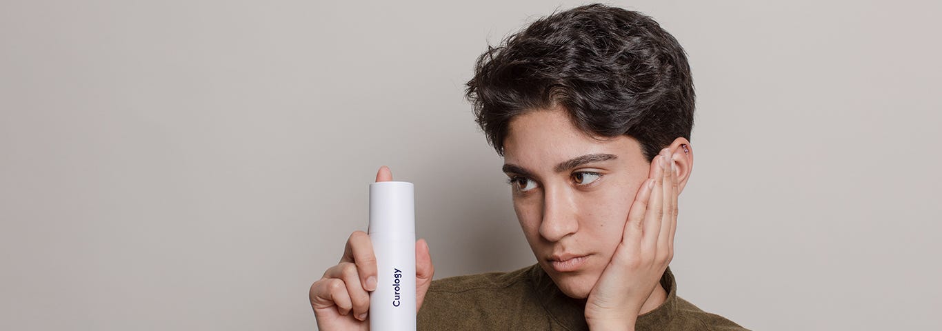 Person holding the Curology superbottle, a custom skincare formula made just for you—unlike drugstore skincare