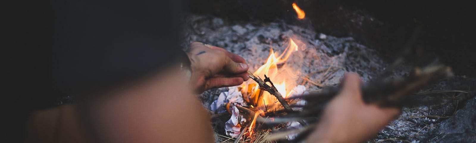 man adding sticks to a fire