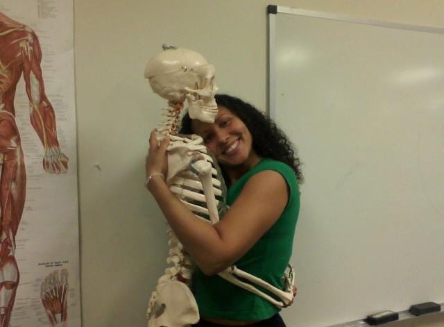 I am the woman smiling on the right hugging a skeleton that is on the left side of the photo. My head is pressed against the skeleton’s chest.