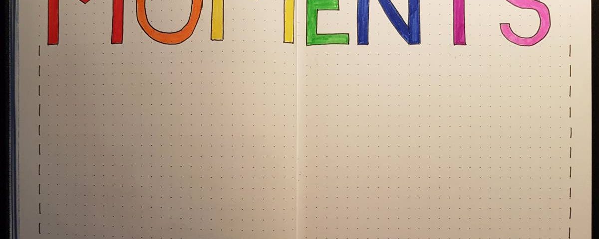An image of a double page in my bullet journal, with the word ‘MOMENTS’ written in rainbow colors across the top of the two pages.