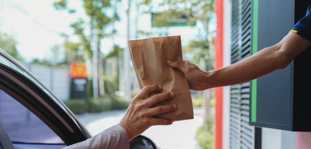 Man picking up food at drive thru window at fast food restaurant