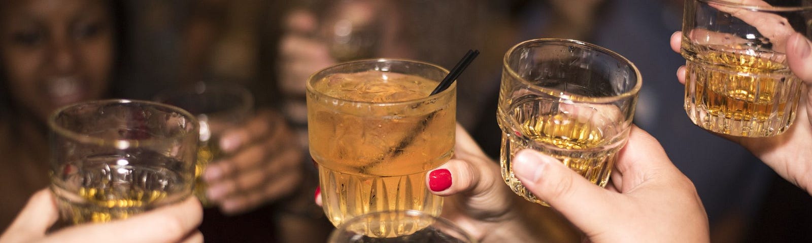 Five people holding their drinks up as a toast.